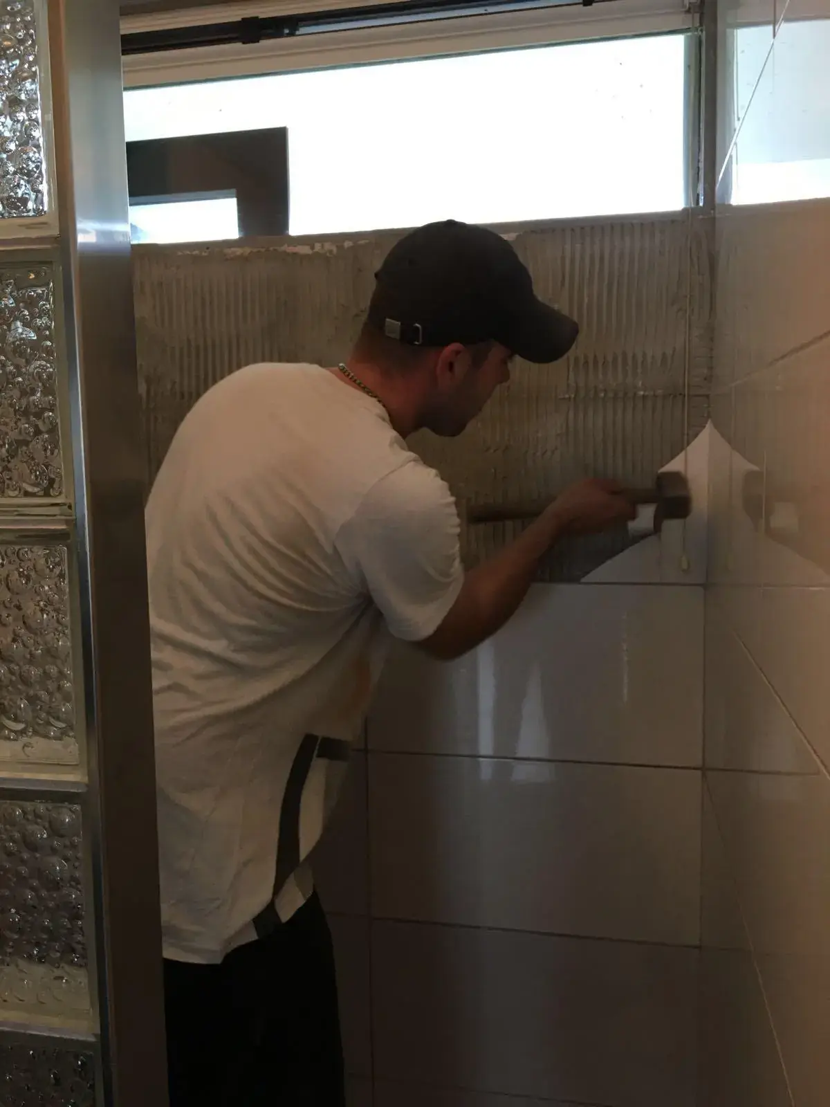 Vakman van Klusbedrijf Biever aan het tegelwerk in een badkamer